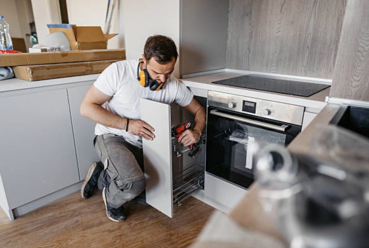 Fitter installing a pull-out cabinet mechanism