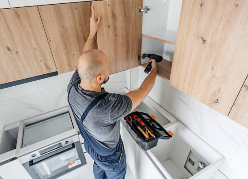 Fitter securing a wall cabinet and adjusting the door