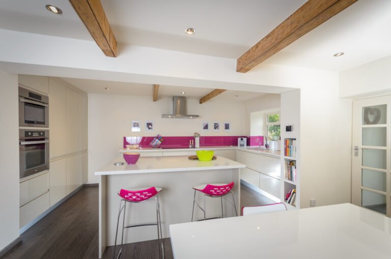 White handleless kitchen with exposed ceiling beams and island with bar stools