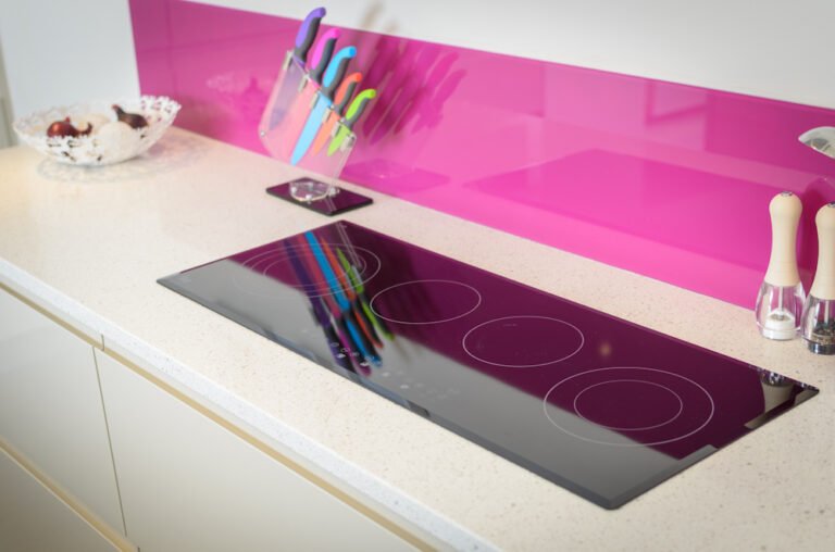 White quartz worktop with induction hob and pink glass splashback