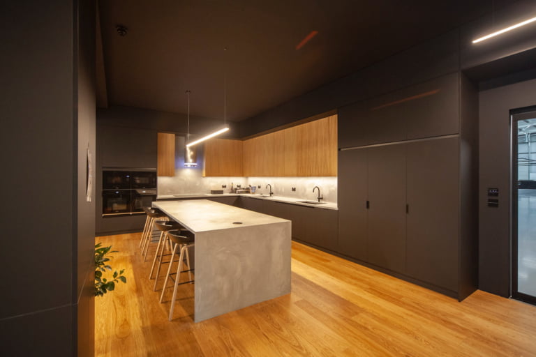 Dark handleless kitchen with oak wall units and concrete-effect island
