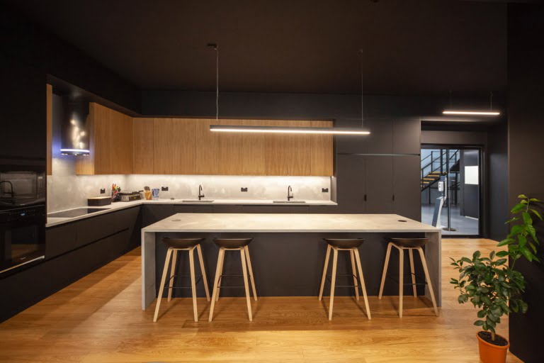 Black and oak kitchen with island seating and linear pendant light