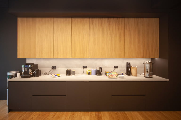 Oak wall units above dark handleless base units with white worktop