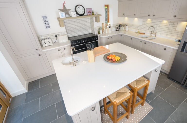 Grey shaker kitchen with white island, range cooker and slate floor