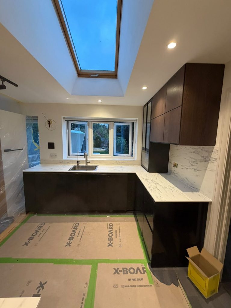 L-shaped marble-effect worktop with inset sink under the window and matching window upstand