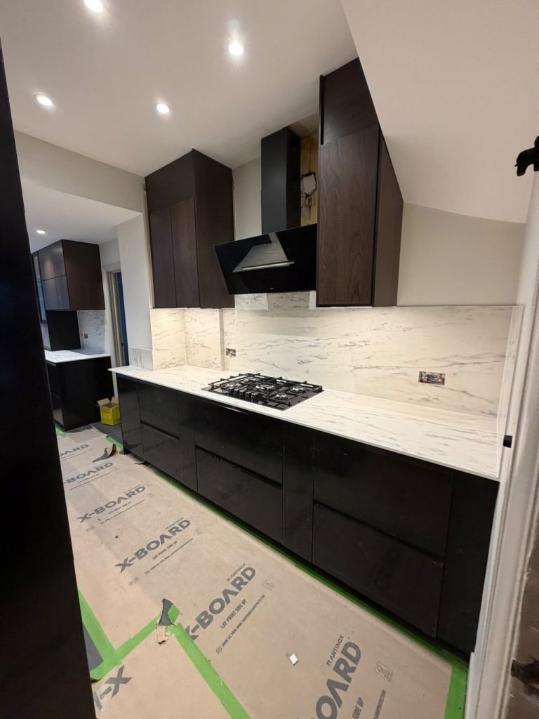 Finished IKEA kitchen with white marble-effect worktop and matching full-height splashback behind a gas hob