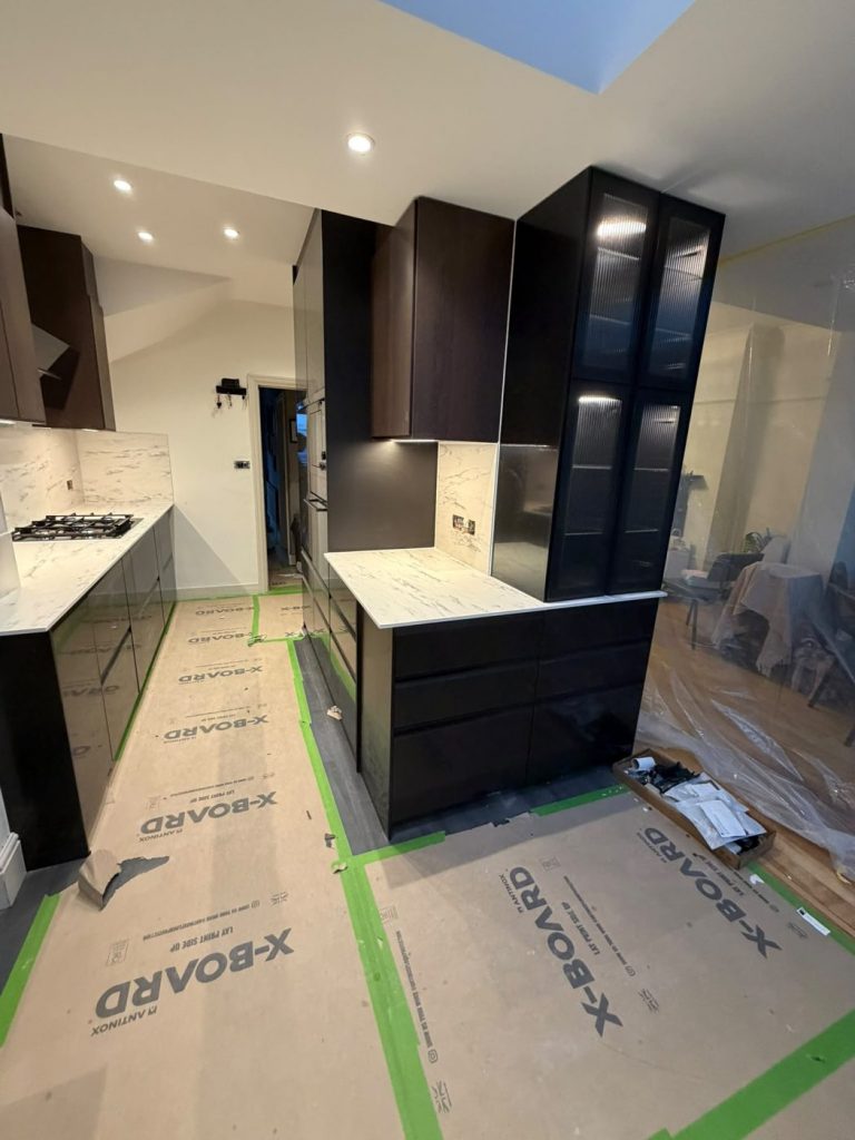 Dark IKEA tall units and glass cabinets with marble-effect worktop and splashback