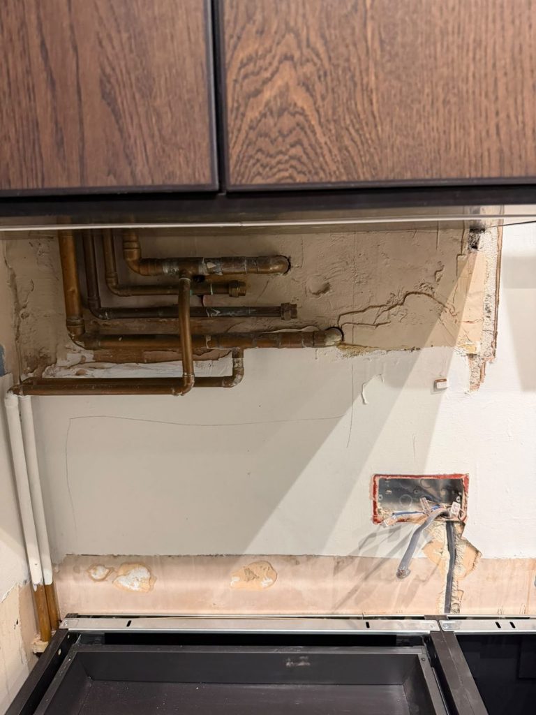 Exposed copper pipework running across the kitchen wall above IKEA base units