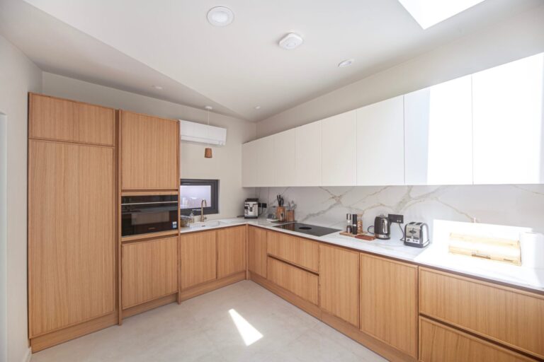 Oak veneer L-shaped kitchen with white wall units and marble-effect splashback