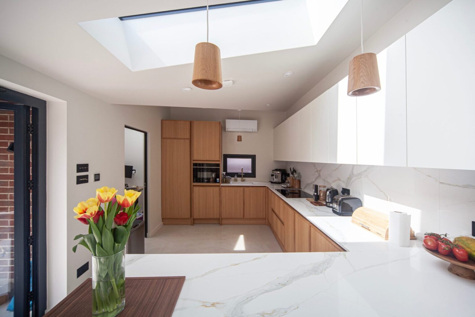 Oak and white kitchen with marble-effect island and skylight, installed by Urban Kitchens