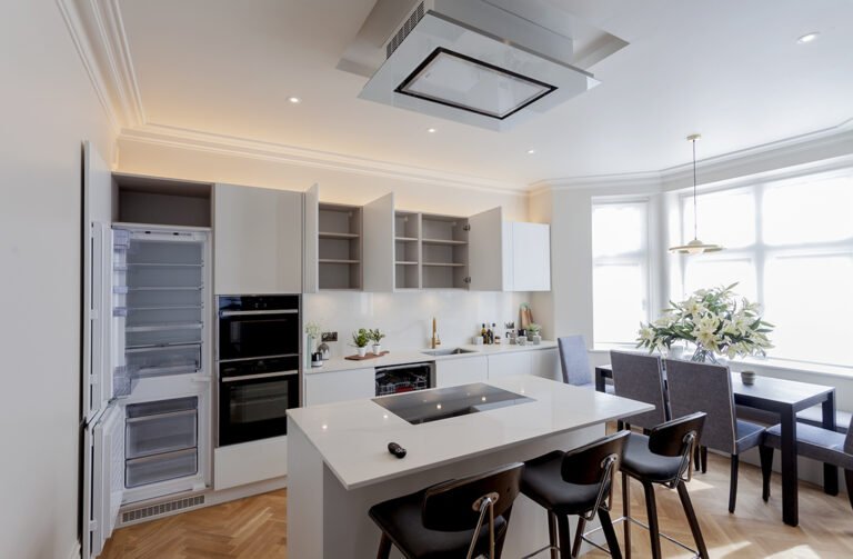 Handleless white kitchen with integrated appliances and island in Hampstead