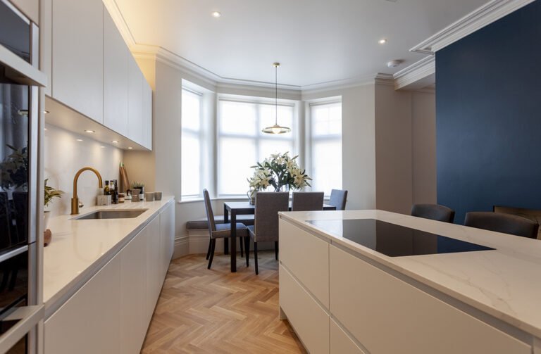 Long white kitchen run with brass tap, island and herringbone floor in Hampstead NW3