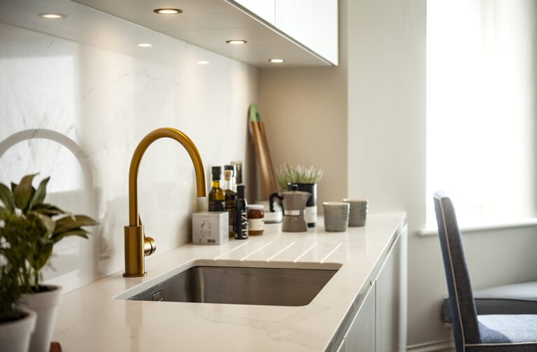 Brass kitchen tap and undermount sink in a white quartz worktop