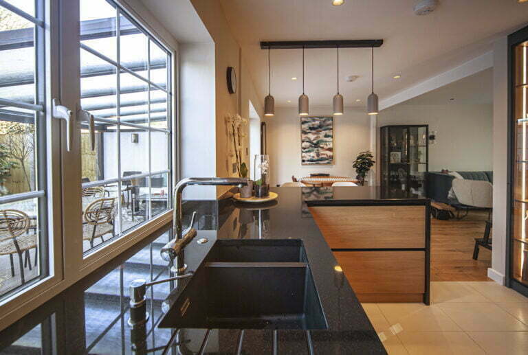 Black worktop with undermount sink beside floor-to-ceiling glazing