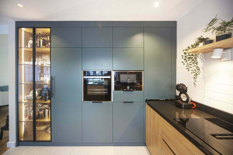 Blue-grey tall units with glass display cabinet, built-in ovens and oak base units