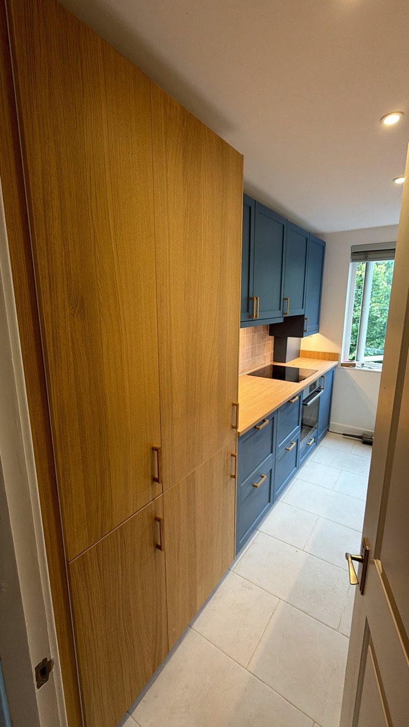 IKEA kitchen installation in Battersea — oak tall units beside navy cabinets