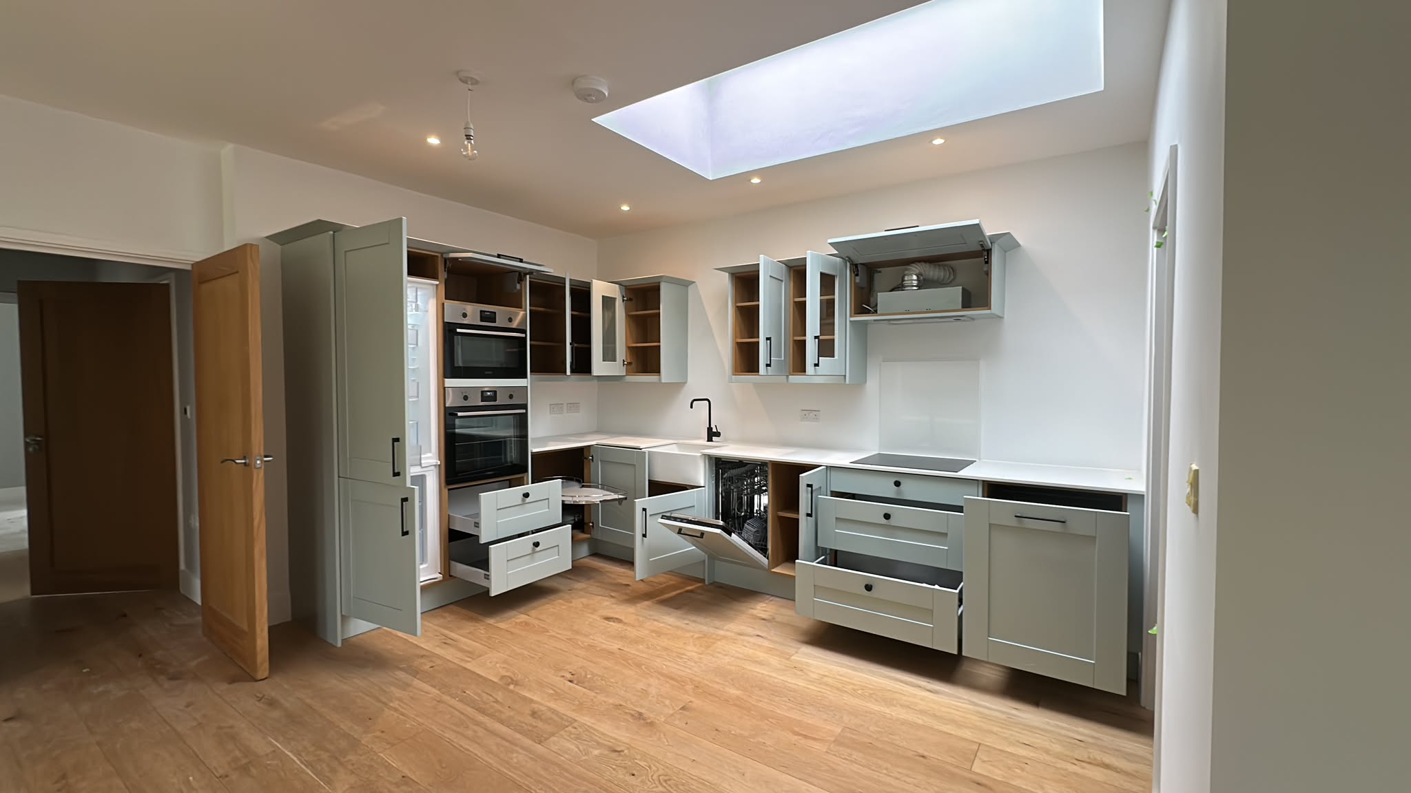 Wren shaker kitchen part-way through installation in a London home, units levelled and built-in ovens going in